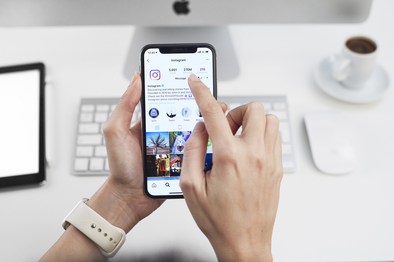 A person holding a smartphone displaying an Instagram profile with a marketing advertisement.