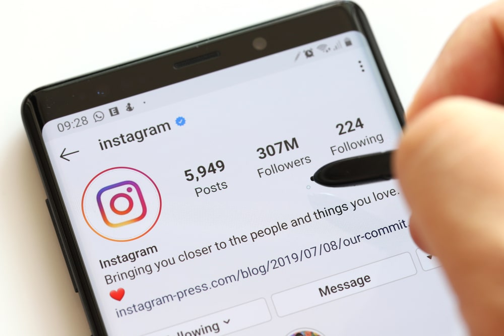 A person using a smartphone with the Instagram app open, showing a post with comments.